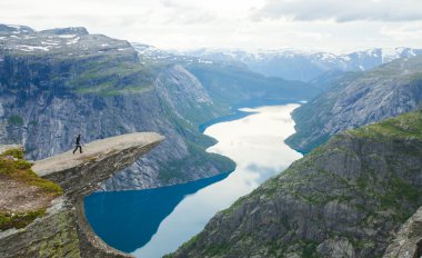 Yürüyüş yer - trolltunga, troller dil, bir turist ile kaya skjegedall ve göl ringedalsvatnet ve dağ panoramik manzara epik görünümü, Norveç ünlü Norveçli canlı bir resmini