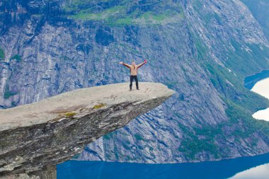 Yürüyüş yer - trolltunga, troller dil, bir turist ile kaya skjegedall ve göl ringedalsvatnet ve dağ panoramik manzara epik görünümü, Norveç ünlü Norveçli canlı bir resmini