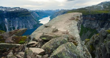 Yürüyüş yer - trolltunga, troller dil, bir turist ile kaya skjegedall ve göl ringedalsvatnet ve dağ panoramik manzara epik görünümü, Norveç ünlü Norveçli canlı bir resmini