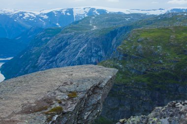 Yürüyüş yer - trolltunga, troller dil, bir turist ile kaya skjegedall ve göl ringedalsvatnet ve dağ panoramik manzara epik görünümü, Norveç ünlü Norveçli canlı bir resmini