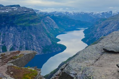 Yürüyüş yer - trolltunga, troller dil, bir turist ile kaya skjegedall ve göl ringedalsvatnet ve dağ panoramik manzara epik görünümü, Norveç ünlü Norveçli canlı bir resmini
