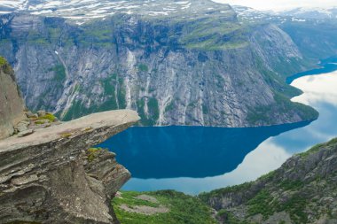 Yürüyüş yer - trolltunga, troller dil, bir turist ile kaya skjegedall ve göl ringedalsvatnet ve dağ panoramik manzara epik görünümü, Norveç ünlü Norveçli canlı bir resmini