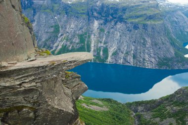 Yürüyüş yer - trolltunga, troller dil, bir turist ile kaya skjegedall ve göl ringedalsvatnet ve dağ panoramik manzara epik görünümü, Norveç ünlü Norveçli canlı bir resmini