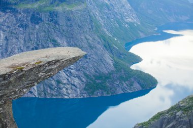 Yürüyüş yer - trolltunga, troller dil, bir turist ile kaya skjegedall ve göl ringedalsvatnet ve dağ panoramik manzara epik görünümü, Norveç ünlü Norveçli canlı bir resmini