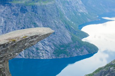 Yürüyüş yer - trolltunga, troller dil, bir turist ile kaya skjegedall ve göl ringedalsvatnet ve dağ panoramik manzara epik görünümü, Norveç ünlü Norveçli canlı bir resmini