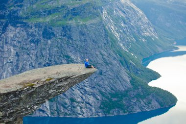 Yürüyüş yer - trolltunga, troller dil, bir turist ile kaya skjegedall ve göl ringedalsvatnet ve dağ panoramik manzara epik görünümü, Norveç ünlü Norveçli canlı bir resmini