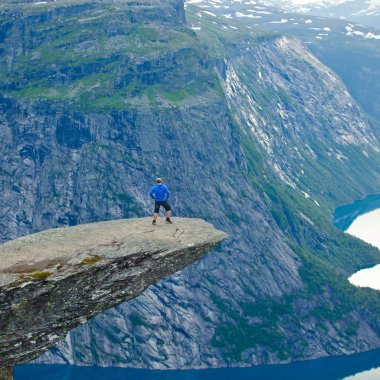 Yürüyüş yer - trolltunga, troller dil, bir turist ile kaya skjegedall ve göl ringedalsvatnet ve dağ panoramik manzara epik görünümü, Norveç ünlü Norveçli canlı bir resmini