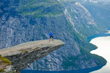 Yürüyüş yer - trolltunga, troller dil, bir turist ile kaya skjegedall ve göl ringedalsvatnet ve dağ panoramik manzara epik görünümü, Norveç ünlü Norveçli canlı bir resmini
