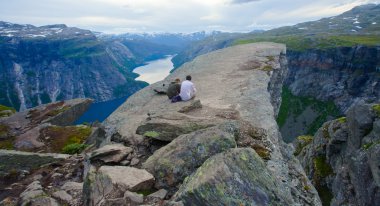 Yürüyüş yer - trolltunga, troller dil, bir turist ile kaya skjegedall ve göl ringedalsvatnet ve dağ panoramik manzara epik görünümü, Norveç ünlü Norveçli canlı bir resmini