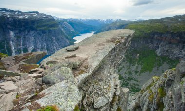 Yürüyüş yer - trolltunga, troller dil, bir turist ile kaya skjegedall ve göl ringedalsvatnet ve dağ panoramik manzara epik görünümü, Norveç ünlü Norveçli canlı bir resmini
