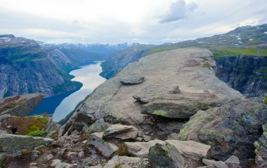 Yürüyüş yer - trolltunga, troller dil, bir turist ile kaya skjegedall ve göl ringedalsvatnet ve dağ panoramik manzara epik görünümü, Norveç ünlü Norveçli canlı bir resmini