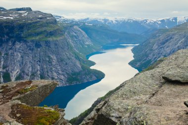 Yürüyüş yer - trolltunga, troller dil, bir turist ile kaya skjegedall ve göl ringedalsvatnet ve dağ panoramik manzara epik görünümü, Norveç ünlü Norveçli canlı bir resmini