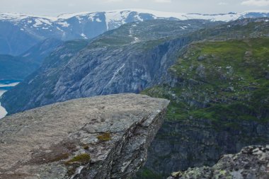 Yürüyüş yer - trolltunga, troller dil, bir turist ile kaya skjegedall ve göl ringedalsvatnet ve dağ panoramik manzara epik görünümü, Norveç ünlü Norveçli canlı bir resmini