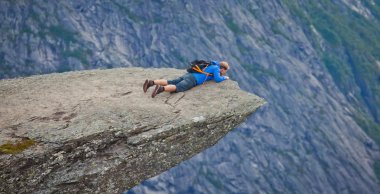 Yürüyüş yer - trolltunga, troller dil, bir turist ile kaya skjegedall ve göl ringedalsvatnet ve dağ panoramik manzara epik görünümü, Norveç ünlü Norveçli canlı bir resmini