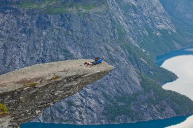 Yürüyüş yer - trolltunga, troller dil, bir turist ile kaya skjegedall ve göl ringedalsvatnet ve dağ panoramik manzara epik görünümü, Norveç ünlü Norveçli canlı bir resmini