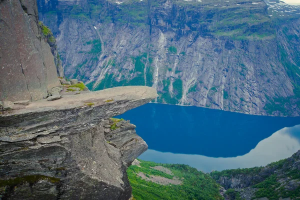 A vibrant picture of famous norwegian hiking place - trolltunga, the trolls tongue, rock skjegedall, with a tourist, and lake ringedalsvatnet and mountain panoramic scenery epic view, Norway — Stock Photo, Image