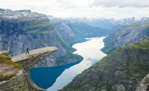 Una imagen vibrante del famoso lugar de senderismo noruego - trolltunga, la lengua trolls, roca skjegedall, con un turista, y el lago ringedalsvatnet y paisajes panorámicos de montaña vista épica, Noruega — Foto de Stock