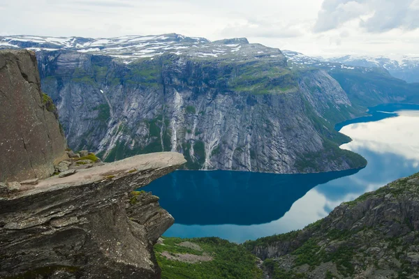 A vibrant picture of famous norwegian hiking place - trolltunga, the trolls tongue, rock skjegedall, with a tourist, and lake ringedalsvatnet and mountain panoramic scenery epic view, Norway — Stock Photo, Image