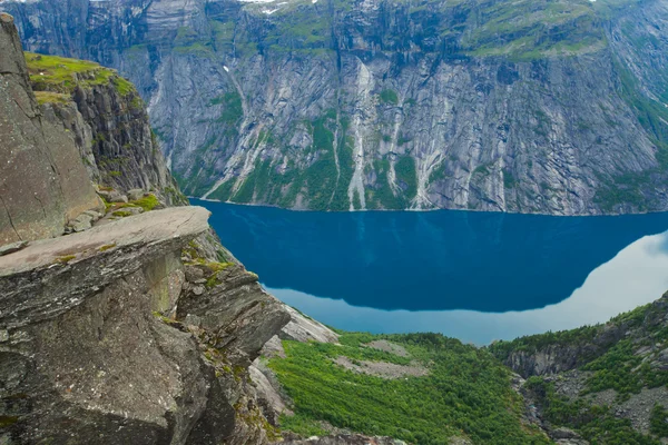 A vibrant picture of famous norwegian hiking place - trolltunga, the trolls tongue, rock skjegedall, with a tourist, and lake ringedalsvatnet and mountain panoramic scenery epic view, Norway — Stock Photo, Image