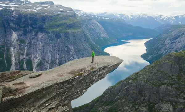 Yürüyüş yer - trolltunga, troller dil, bir turist ile kaya skjegedall ve göl ringedalsvatnet ve dağ panoramik manzara epik görünümü, Norveç ünlü Norveçli canlı bir resmini — Stok fotoğraf