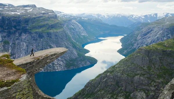 Una imagen vibrante del famoso lugar de senderismo noruego - trolltunga, la lengua trolls, roca skjegedall, con un turista, y el lago ringedalsvatnet y paisajes panorámicos de montaña vista épica, Noruega —  Fotos de Stock