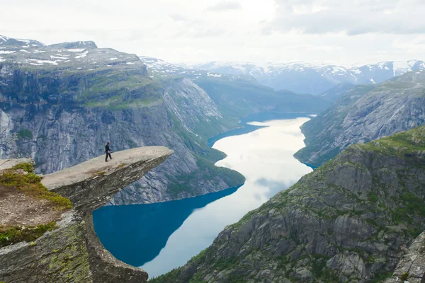 Una imagen vibrante del famoso lugar de senderismo noruego - trolltunga, la lengua trolls, roca skjegedall, con un turista, y el lago ringedalsvatnet y paisajes panorámicos de montaña vista épica, Noruega —  Fotos de Stock