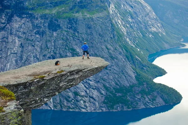 Żywy obraz słynnego norweskiego miejsce - Język trolla, język trolli, skała skjegedall, z turystą, oraz jezioro ringedalsvatnet i góry panoramiczny pejzaż epicki widok, Norwegia — Zdjęcie stockowe