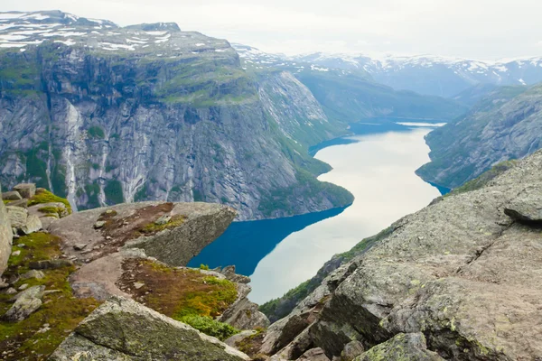 Una imagen vibrante del famoso lugar de senderismo noruego - trolltunga, la lengua trolls, roca skjegedall, con un turista, y el lago ringedalsvatnet y paisajes panorámicos de montaña vista épica, Noruega —  Fotos de Stock