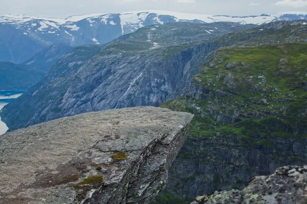 Una imagen vibrante del famoso lugar de senderismo noruego - trolltunga, la lengua trolls, roca skjegedall, con un turista, y el lago ringedalsvatnet y paisajes panorámicos de montaña vista épica, Noruega — Foto de Stock