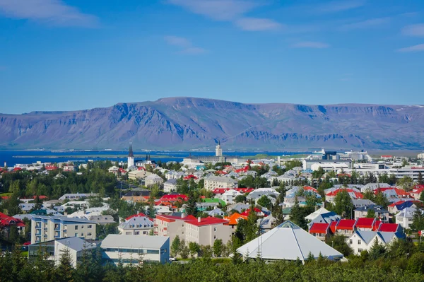 Hermosa vista aérea super gran angular de Reykjavik, Islandia, con el puerto y el horizonte montañas y paisajes más allá de la ciudad, visto desde la torre de observación de la catedral de Hallgrimskirkja . — Foto de Stock