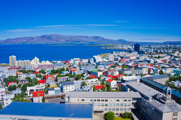 Hermosa vista aérea super gran angular de Reykjavik, Islandia, con el puerto y el horizonte montañas y paisajes más allá de la ciudad, visto desde la torre de observación de la catedral de Hallgrimskirkja . — Foto de Stock