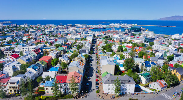 Beautiful super wide-angle aerial view of Reykjavik, Iceland with harbor and skyline mountains and scenery beyond the city, seen from the observation tower of Hallgrimskirkja Cathedral.