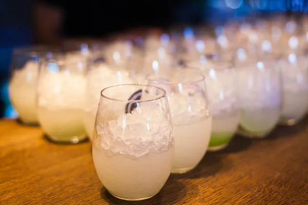 Vackra linje av olika färgade cocktails med rök på en utomhus part, tequila, martini, vodka och andra på inredda catering bukett bord på utomhus julfest — Stockfoto