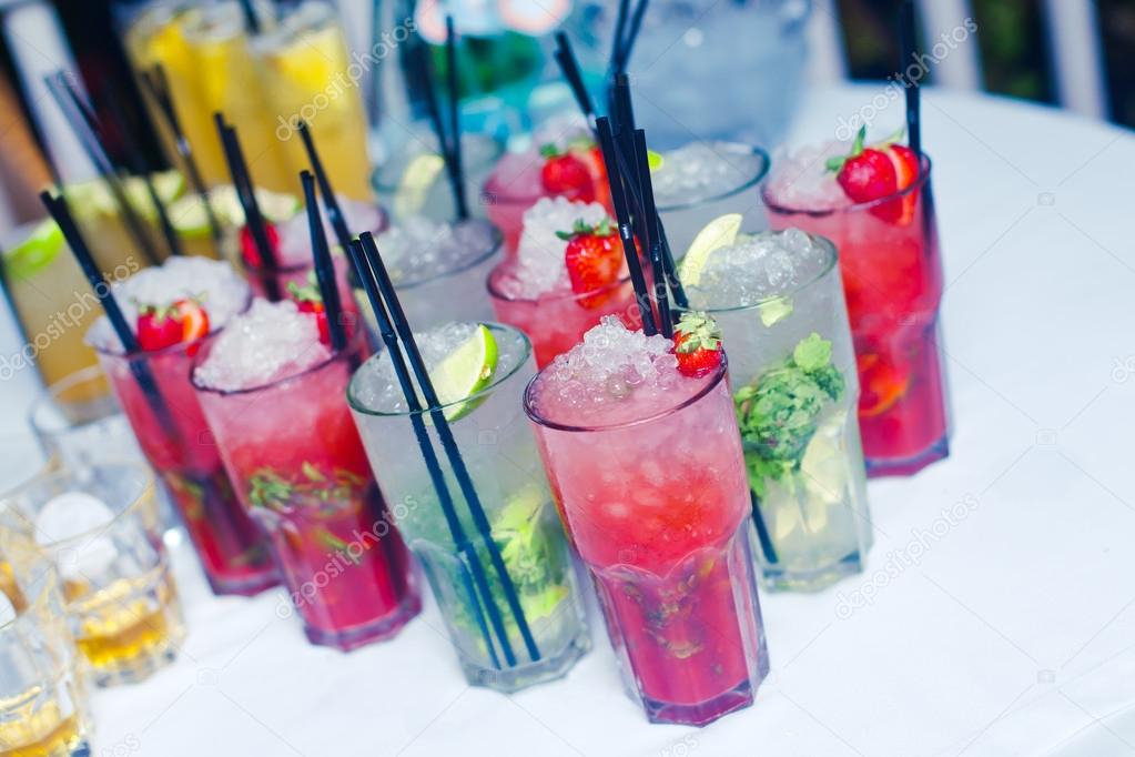 Beautiful line of different coloured cocktails with smoke on a open air party, tequila, martini, vodka, and others on decorated catering bouquet table on open air christmas party