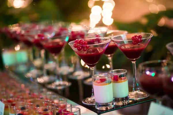 Beautiful line of different colored cocktails with smoke on a Christmas party, tequila, martini, vodka, and others on decorated catering bouquet table on open air party