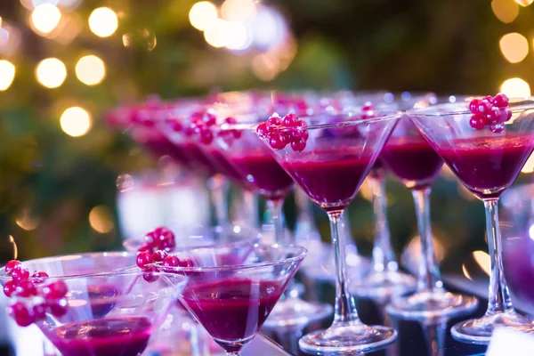 Hermosa línea de cócteles de diferentes colores con humo en una fiesta de Navidad, tequila, martini, vodka y otros en la mesa de ramo de catering decorado en la fiesta al aire libre — Foto de Stock