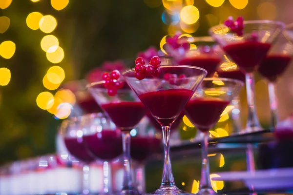 Hermosa línea de cócteles de diferentes colores con humo en una fiesta de Navidad, tequila, martini, vodka y otros en la mesa de ramo de catering decorado en la fiesta al aire libre —  Fotos de Stock