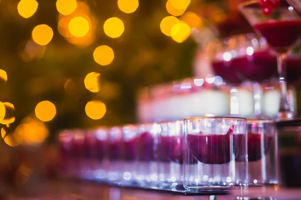 Hermosa línea de cócteles de diferentes colores con humo en una fiesta de Navidad, tequila, martini, vodka y otros en la mesa de ramo de catering decorado en la fiesta al aire libre —  Fotos de Stock