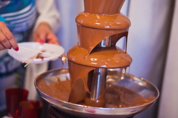 Vibrant Picture of Chocolate Fountain Fontain on childen kids birthday party with a kids playing around and marshmallows and fruits dip dipping into fountain — Stock Photo, Image