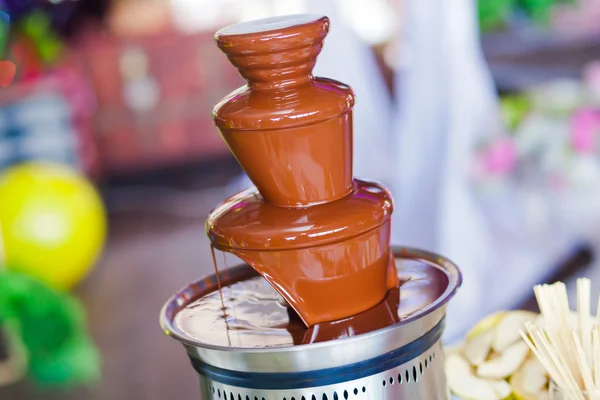 Vibrant Picture of Chocolate Fountain Fontain on childen kids birthday party with a kids playing around and marshmallows and fruits dip dipping into fountain — Stock Photo, Image