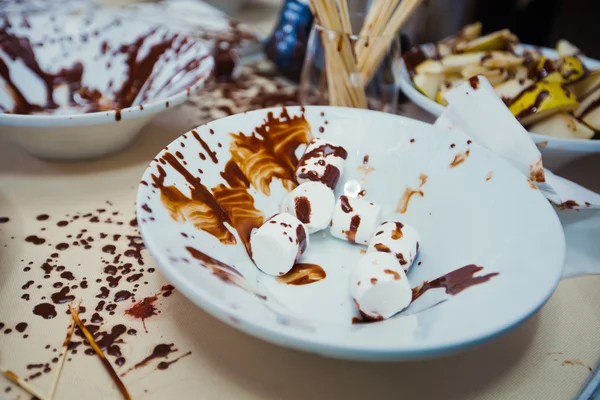 Vibrant Picture of Chocolate Fountain Fontain on childen kids birthday party with a kids playing around and marshmallows and fruits dip dipping into fountain — Stock Photo, Image