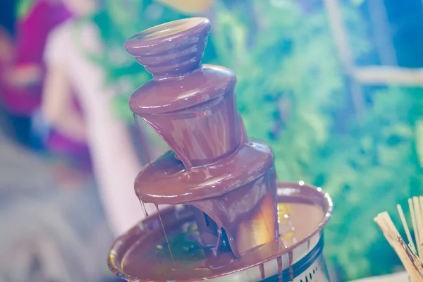 Vibrant Picture of Chocolate Fountain Fontain on childen kids birthday party with a kids playing around and marshmallows and fruits dip dipping into fountain — Stock Photo, Image