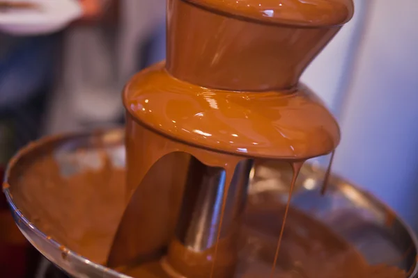 Vibrant Picture of Chocolate Fountain Fontain on childen kids birthday party with a kids playing around and marshmallows and fruits dip dipping into fountain — Stock Photo, Image