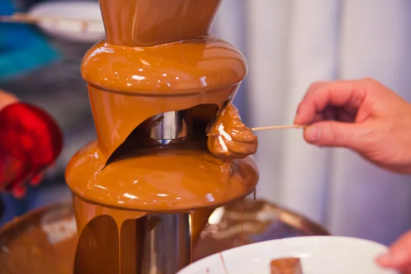 Vibrant Picture of Chocolate Fountain Fontain on childen kids birthday party with a kids playing around and marshmallows and fruits dip dipping into fountain — Stock Photo, Image