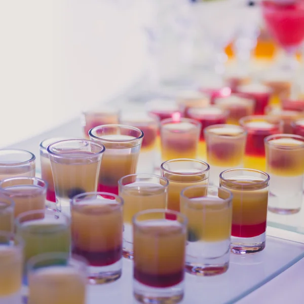 Bela linha de coquetéis de álcool coloridos diferentes com hortelã em uma festa de Natal, martini, vodka e outros na mesa de buquê de catering decorada em evento ao ar livre — Fotografia de Stock