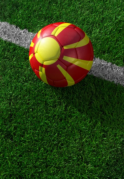 Fotbalový míč a státní vlajka Makedonie, zelené trávy — Stock fotografie