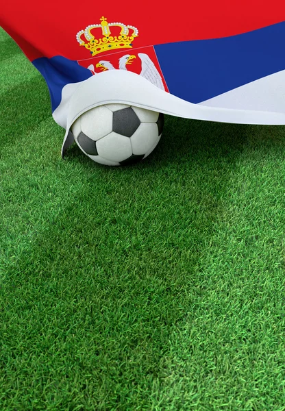Fotbalový míč a státní vlajka Srbska, zelené trávy — Stock fotografie