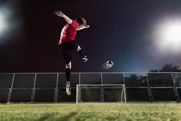 Athlete kicking soccer ball towards goal — Stock Photo, Image