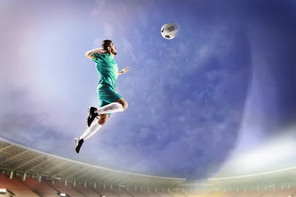 Athlete heading soccer ball in stadium — Stock Photo, Image