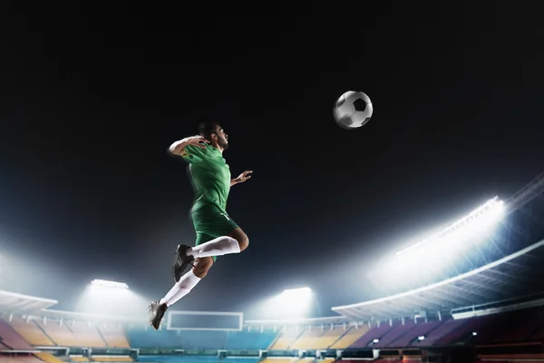 Спортсмен, возглавляющий футбольный мяч на стадионе — стоковое фото